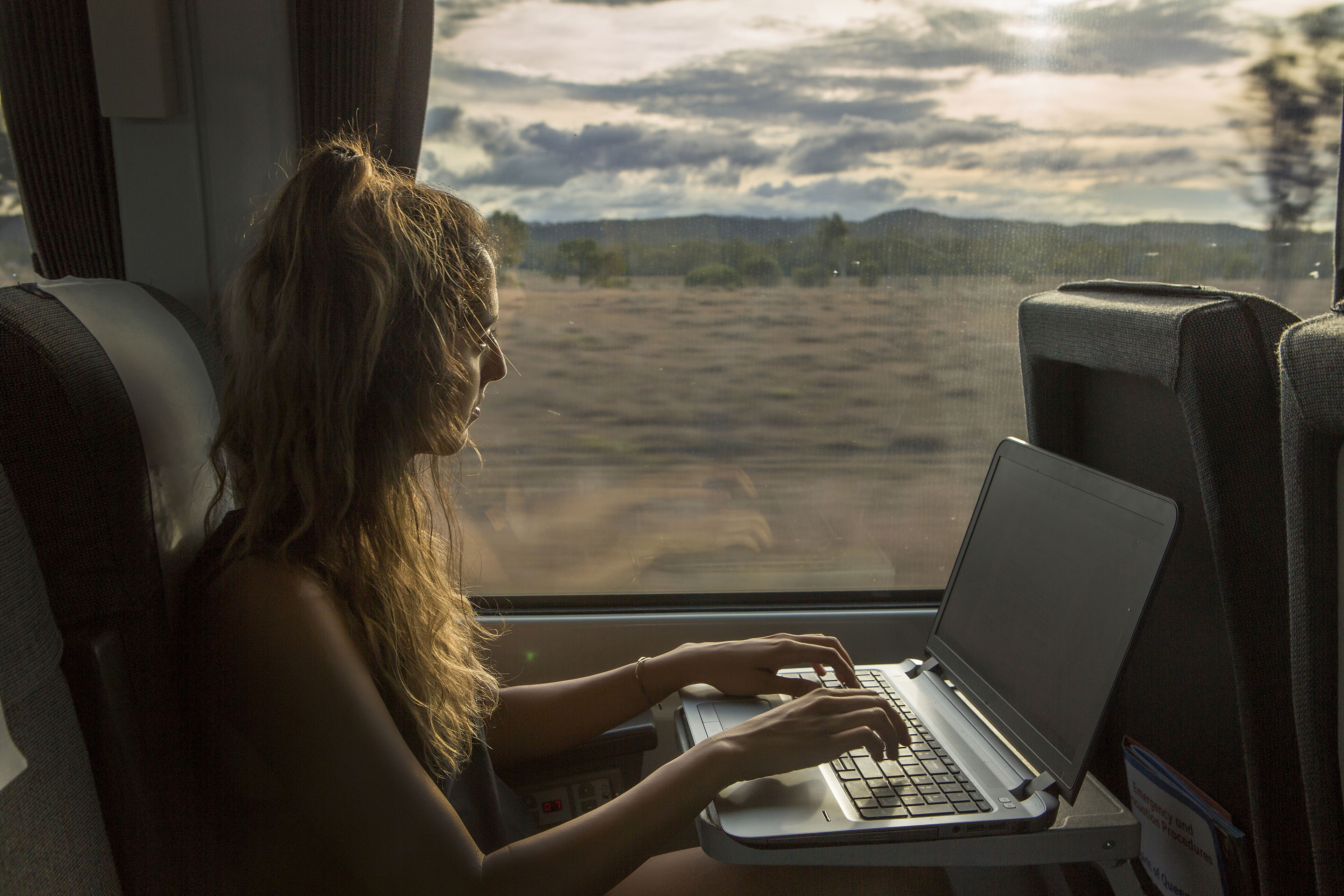 A woman works on her laptop while traveling on a train A woman working on her laptop while traveling on a train