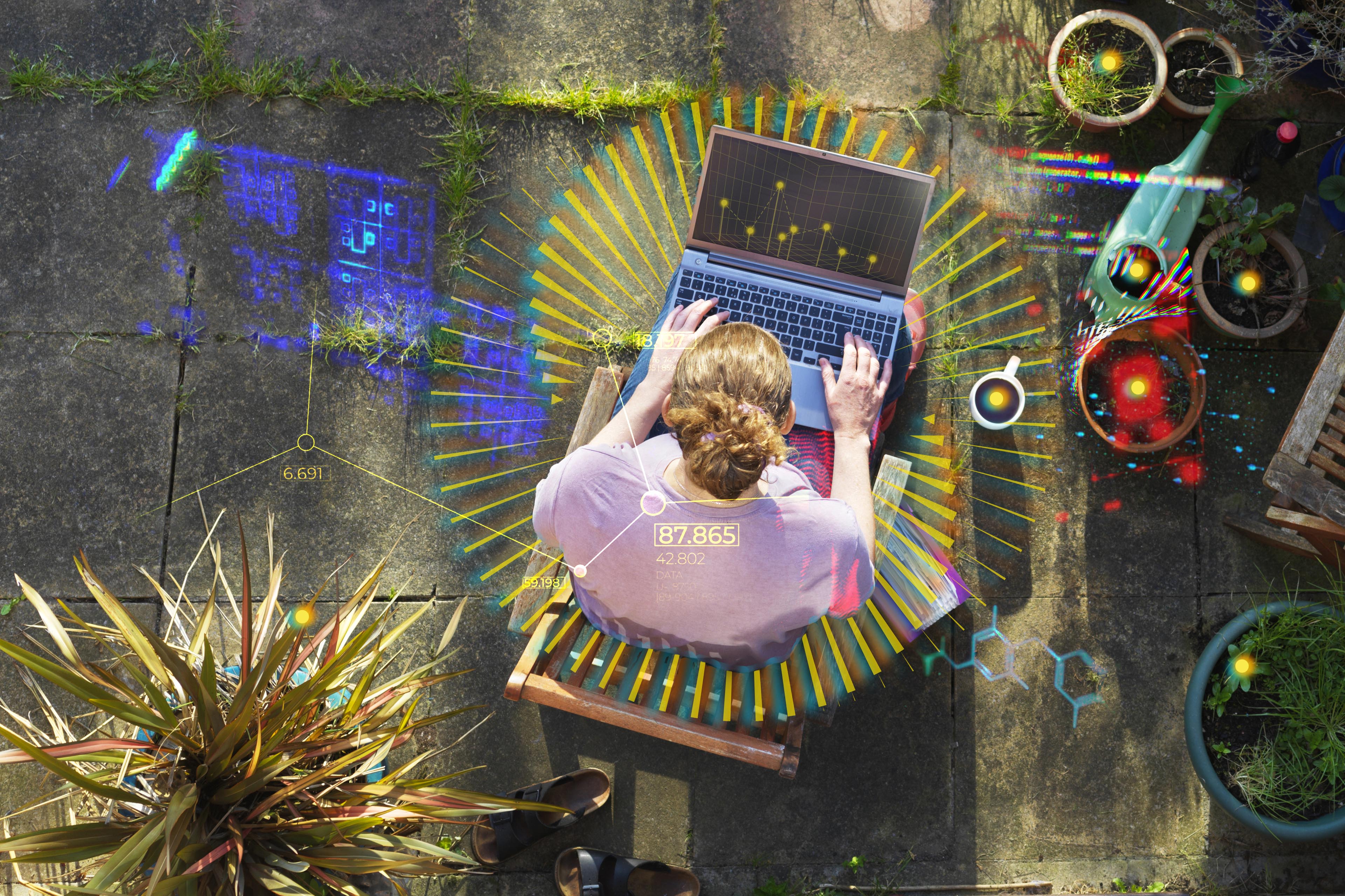 elevated view of a woman working from home in her garden using a laptop computer Elevated view of a woman working from home in her garden using a laptop computer