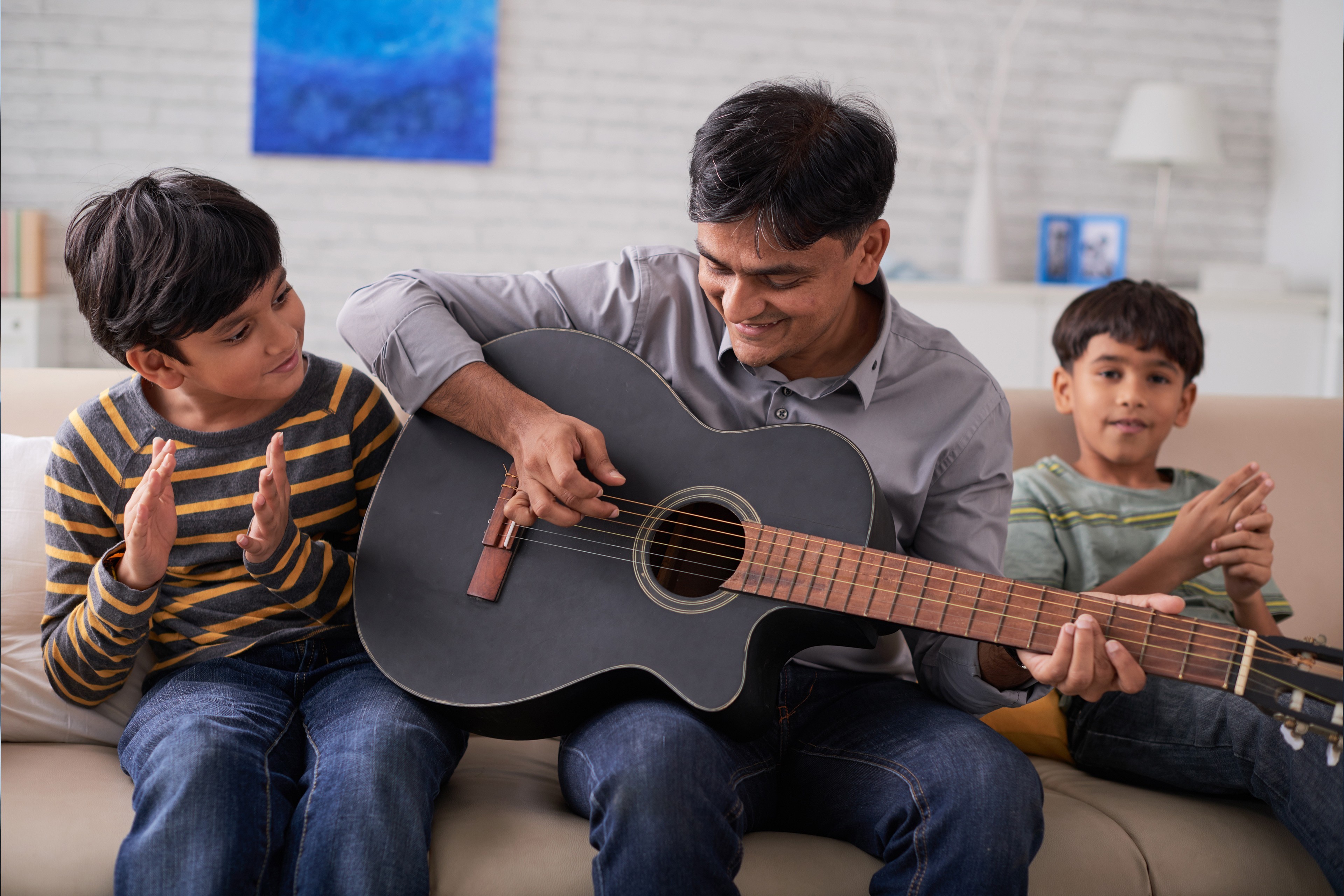 Father playing guitar and his sons singing Father playing guitar and his sons singing