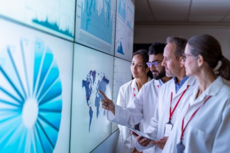 Team of researchers inspecting charts on interactive screens