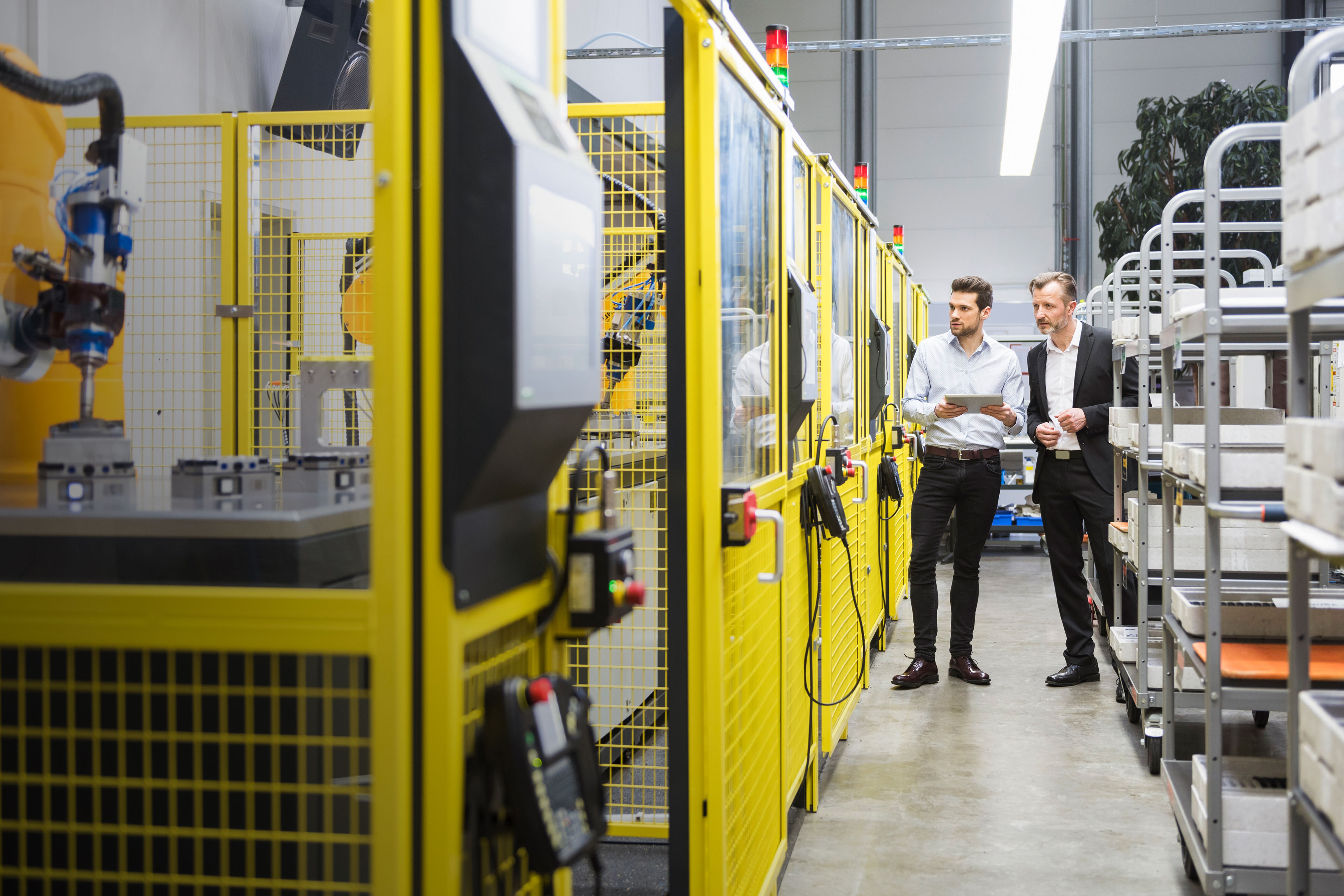 Two businessman observing industrial robots in factory Two businessman observing industrial robots in factory