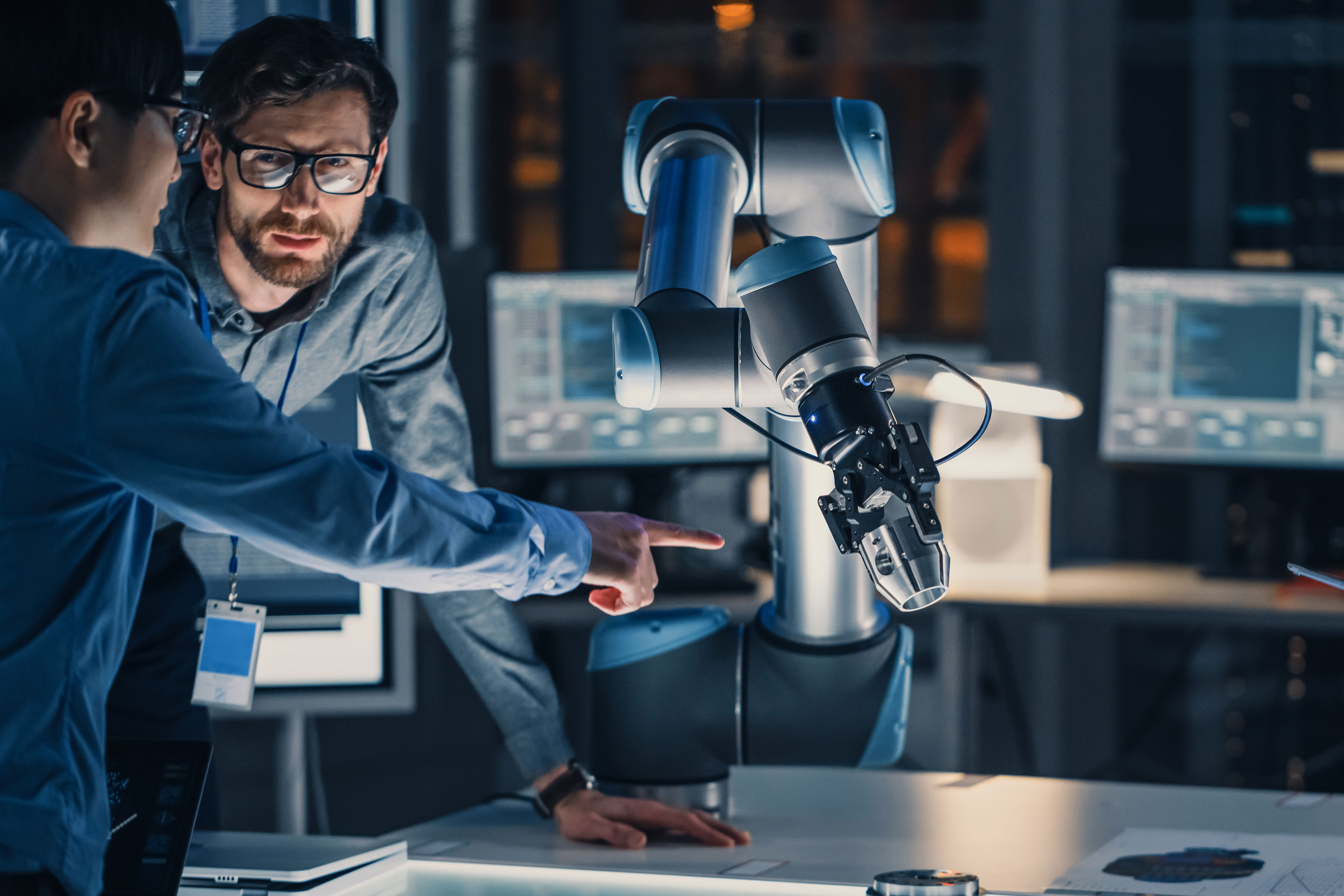 Two technologists in discussion next to machine Two technologists in discussion next to machine