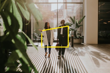 woman and a man talking as they enter an office building