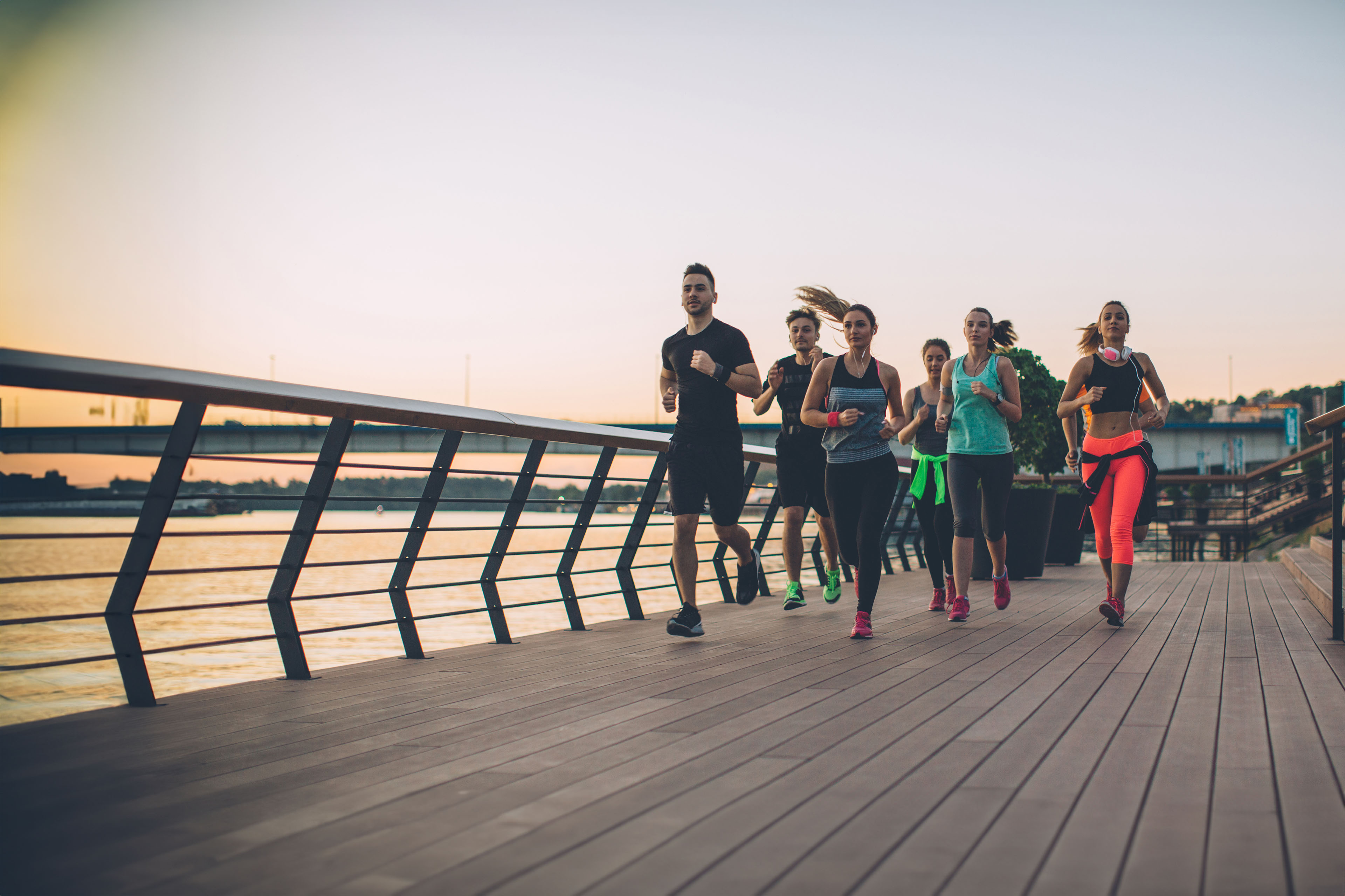 Young men and women running in the city by river
